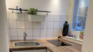 A compact kitchen with white cabinets, a stainless steel sink, wooden countertops, and a window with a view of snow outside. - Historical Town Center Cosy Flat (Colmar)