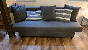 A grey sofa with striped pillows and a wooden floor. - Historical Town Center Cosy Flat (Colmar)