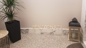 A room with a potted plant, a marble wall, and a sign that reads "BEN TORNATI". - La Casa dei Gemelli (Priolo Gargallo)