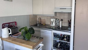 Een compacte keuken met een koffiezetapparaat, waterkoker en een kleine koelkast.