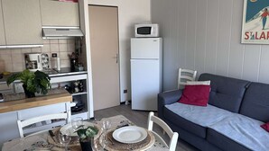 Een kleine woonruimte met een kitchenette, eethoek en een bank.