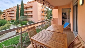 A balcony with a wooden table and chairs, overlooking a residential area with apartment buildings and greenery.