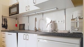A modern kitchen with white cabinets, a microwave, a Bosch coffee maker, and a toaster.