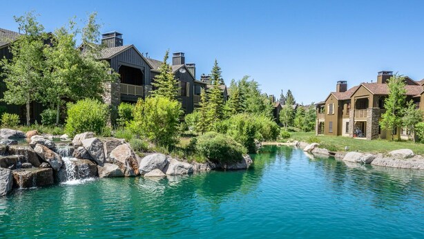 Ett bostadsområde med en flod, hus med balkonger och en vacker natur.