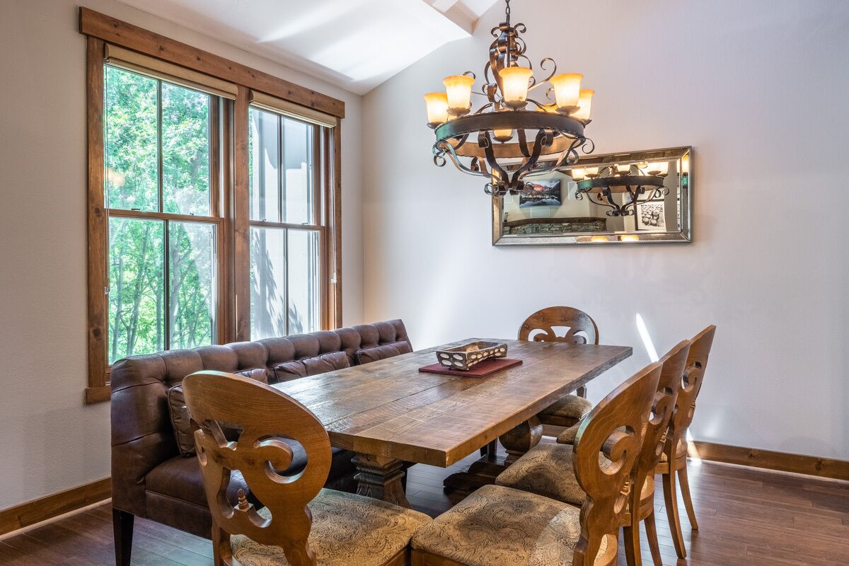 A dining room with a wooden table, cushioned benches, and a chandelier.