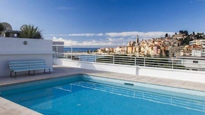 A rooftop swimming pool with a bench, a view of a coastal town, and a clear sky. - Superb air-conditioned apartment with large terrace and parking in Menton (Menton)