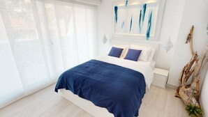 A modern bedroom with a large bed, white walls, and a view through a sliding door. - Superb air-conditioned apartment with large terrace and parking in Menton (Menton)