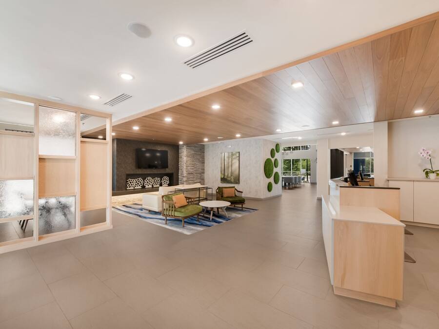A spacious lobby with a reception desk, seating area, and a large wall-mounted TV.