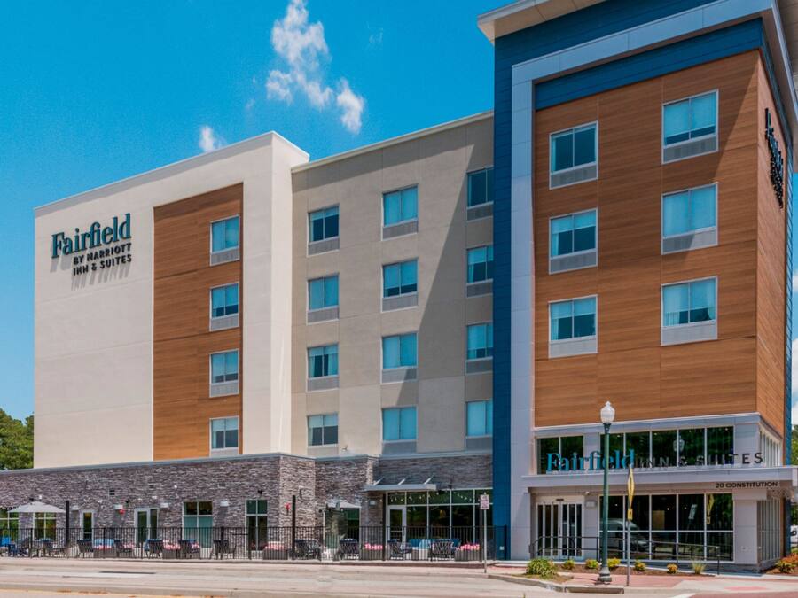 Ein Hotel Fairfield Inn & Suites mit modernem Design, das eine Steinfassade und große Fenster aufweist.