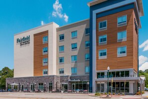 Features a modern design with white and wood paneling, multiple windows, and a ground-level entrance.