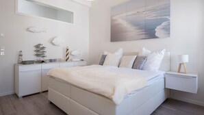 Un dormitorio con una cama grande, una mesita de noche, un aparador, un espejo y un cuadro colgado en la pared.