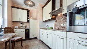 A modern kitchen with white cabinetry, a stainless steel oven, and a marble countertop. - Villa zur See 10 - modern maritime vacation apartment (Heringsdorf (Seebad))