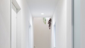 A narrow hallway with white walls and a wooden floor leading to a staircase.