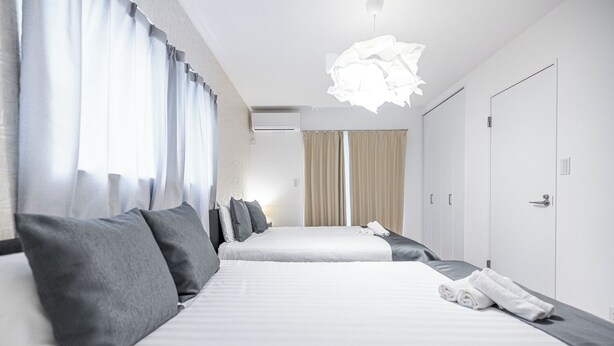 A modern hotel room with a large bed, a bedside table with a lamp, and a wardrobe.