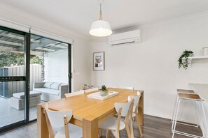 A modern dining area with a wooden table, white chairs, and a hanging pendant light.