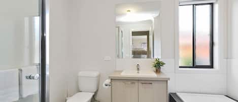 Un baño moderno con inodoro, lavamanos y bañera.