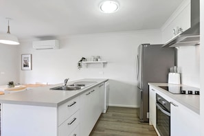 A modern kitchen with white cabinetry, a stainless steel refrigerator, and a built-in oven.