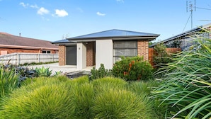 A residential house with a brick facade, a garage door, and a well-maintained garden with various plants.