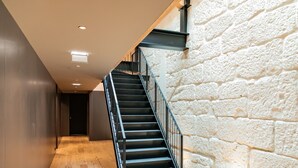 A staircase with black railings and wooden steps leading to a dark doorway. - Ana Sofia Graça Carneiro (Porto)