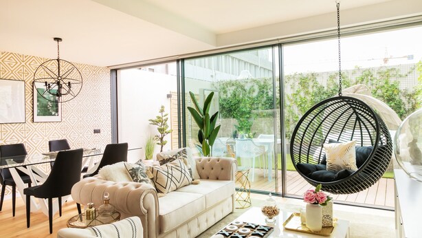 A modern living room with a sofa, dining table, chairs, and a hanging chair. - Ana Sofia Graça Carneiro (Porto)