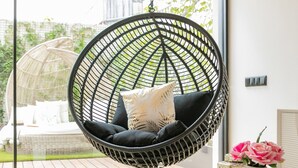 A modern living room with a hanging chair, a coffee table, and a view of the outdoors. - Ana Sofia Graça Carneiro (Porto)