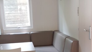 A compact living space with a built-in sofa, a small table, and a window with blinds.