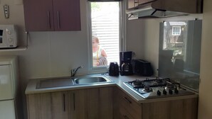 A compact kitchen with a sink, stove, and coffee maker.