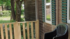 A covered outdoor area with a wooden deck, a black plastic chair, and a wooden fence.