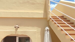 Un bâtiment de couleur beige, avec un escalier, une fenêtre et un lampadaire.