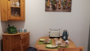 Ein Essbereich mit einem Holztisch, gedeckt für zwei Personen, einem Schrank mit Glastüren und einem an der Wand befestigten Holzbild.