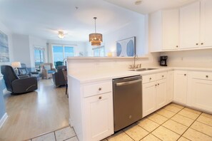 A modern kitchen with white cabinetry, a dishwasher, and a coffee maker. - Spacious Oceanfront and Pier Views~ Seaside Villas 202 (Folly Beach)