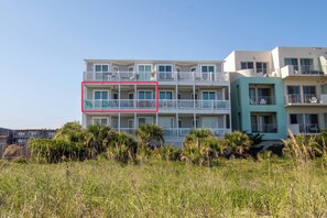 A multi-story residential building with balconies, surrounded by lush greenery. - Spacious Oceanfront and Pier Views~ Seaside Villas 202 (Folly Beach)