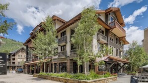 A multi-story building with balconies, a stone-paved plaza, and outdoor seating. - Mill Club 2 Bedroom Condo!!  Ski In/Out in Copper's Center Village!! (Copper Mountain)