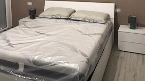 A bedroom with a bed, two bedside tables, and a nightstand. - Case Vacanza "Le Cale - Cala Goloritzè" (Tortolì)