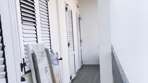 A corridor with white walls, grey wooden flooring, and a metal railing on the right. - Case Vacanza "Le Cale - Cala Goloritzè" (Tortolì)