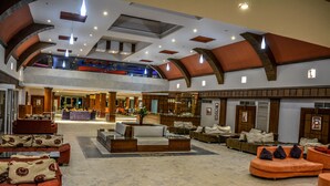 A spacious lobby with multiple seating areas, a reception desk, and a high ceiling with exposed beams. - Retal View Resort El Sokhna (Ataqah)