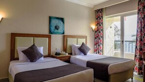A hotel room with two beds, a nightstand, a painting, and a balcony with curtains. - Retal View Resort El Sokhna (Ataqah)