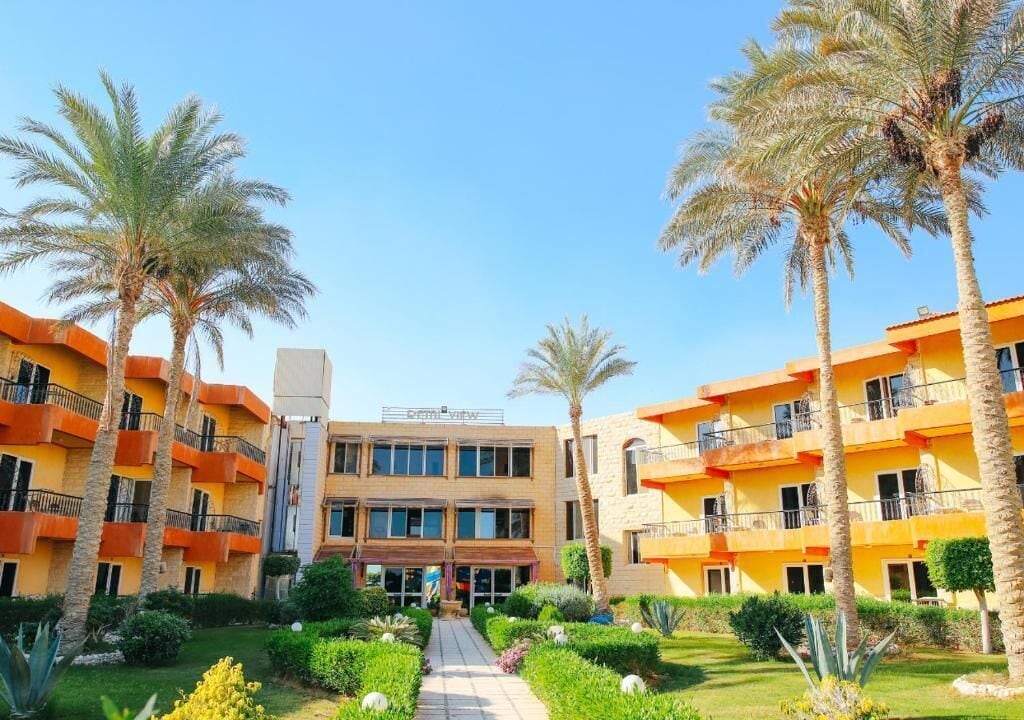 A hotel with multiple floors, a central courtyard, and palm trees.