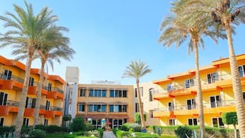 A hotel with multiple floors, a central courtyard, and palm trees.