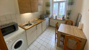 Eine kompakte Küche mit Waschmaschine, Mikrowelle und einer kleinen Essecke mit Tisch und Stühlen.