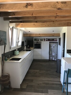 A modern kitchen with white cabinetry, a built-in oven, and a stainless steel refrigerator. - Maison Mango à Capbreton Bien Placée au Bouheben en Bordure de Foret (Capbreton)
