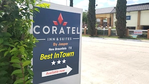 Hotelli Coratel Inn & Suitesin kyltti New Braunfelsissa, Texasissa. Kyltissä on moderni muotoilu, punainen logo ja tähdet, jotka osoittavat hotellin tarjoamat palvelut.