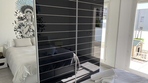 Un dormitorio moderno con una cama grande, una mesita de noche, una obra de arte en la pared y vistas al exterior.