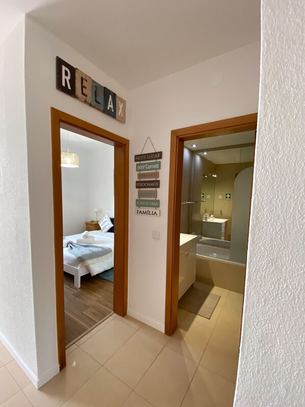 Un pasillo de hotel con una cama en la habitación de la izquierda y un baño en la derecha.