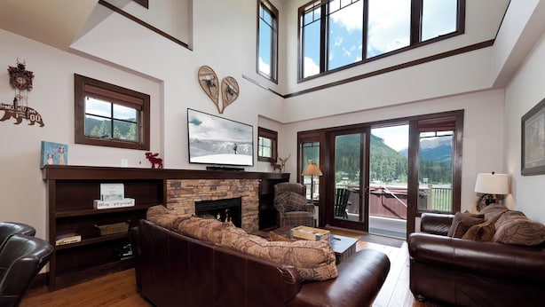 A spacious living room with a fireplace, leather sofas, and a large TV.