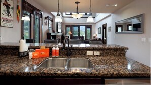 A modern kitchen with granite countertops, a double sink, and pendant lighting.