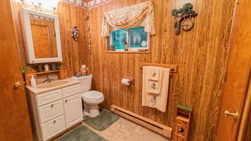 A wooden-paneled bathroom with a toilet, sink, and towel rack.