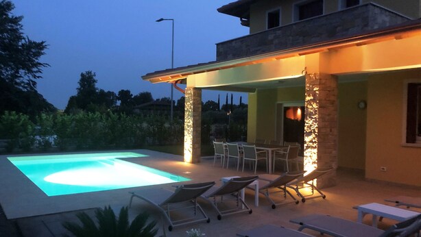 A pool with lounge chairs and a covered patio area. - Villa Massimiliano, with private heated pool and garden (Solarolo)