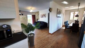 A modern living room with a sofa, a dining area with chairs, and a kitchen area with a microwave. - Villa Massimiliano, with private heated pool and garden (Solarolo)
