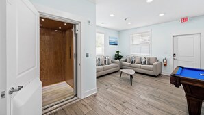 A living room with a pool table, a sofa, and a wooden door leading to a closet. - MAIN EVENT HOME 20beds/19baths CINEMA+AMENITIES+Pool ONLY 350ft to beach!!! (Myrtle Beach)